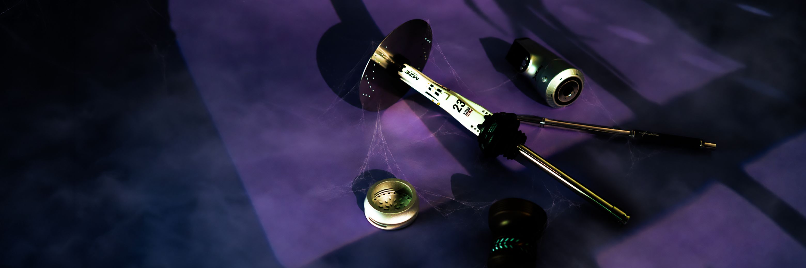 Shisha, Kopf und Zubehör zwischen Spinnweben in violettem Licht